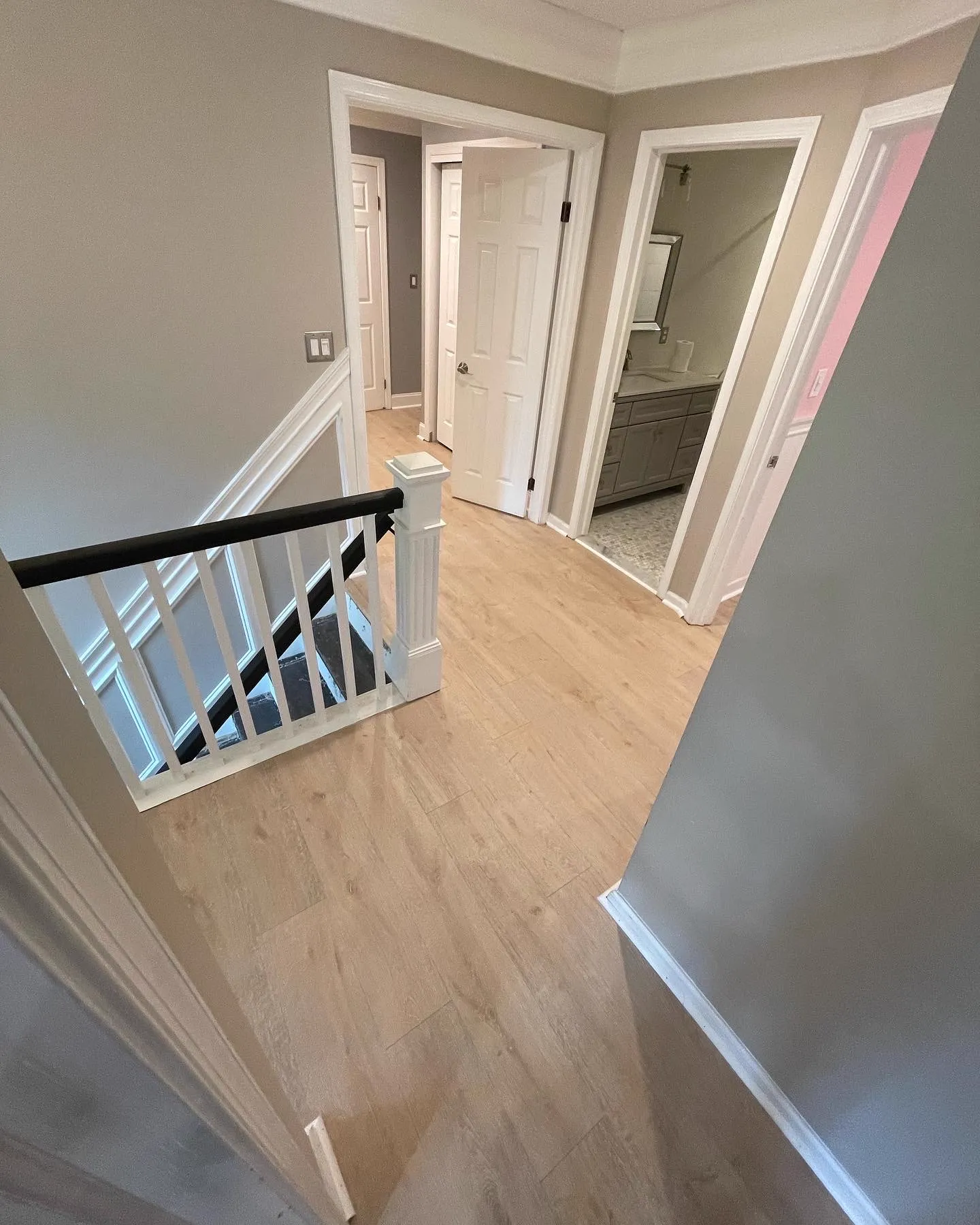 Light oak hardwood landing and hallway with white spindle railing